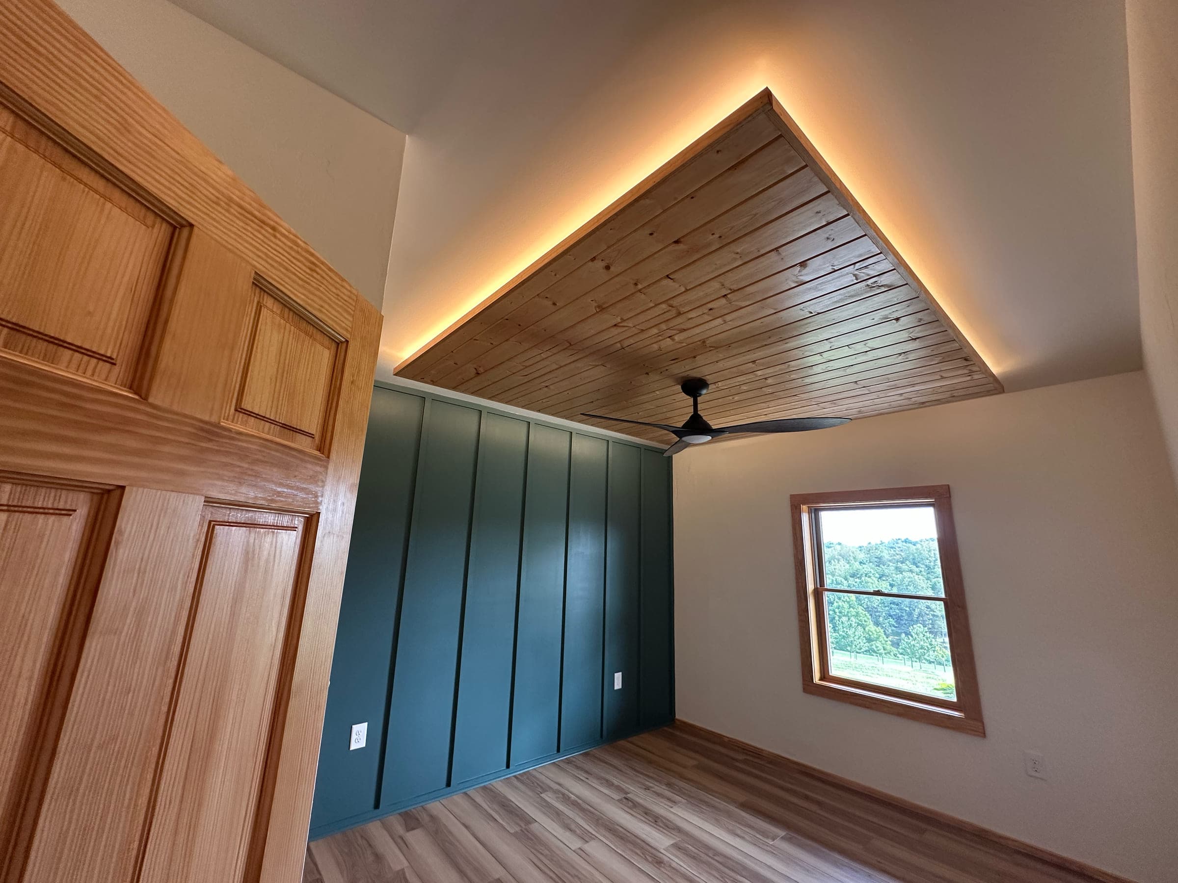 Inverted tray ceiling with LED backlighting over a board and batten accent wall, in the Fincastle basement addition in Botetourt County