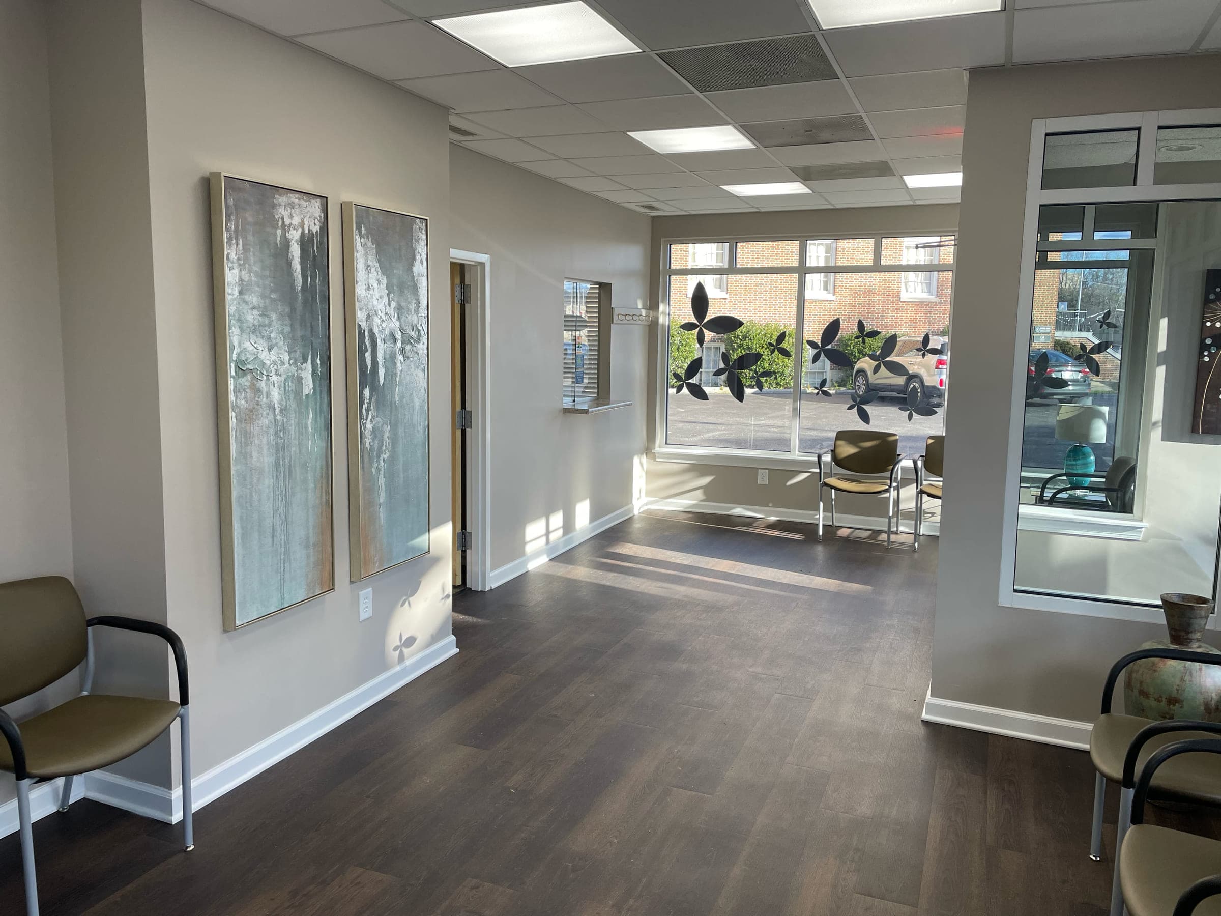 Finished professional waiting room with framed artwork, guest seating and a daylit storefront window